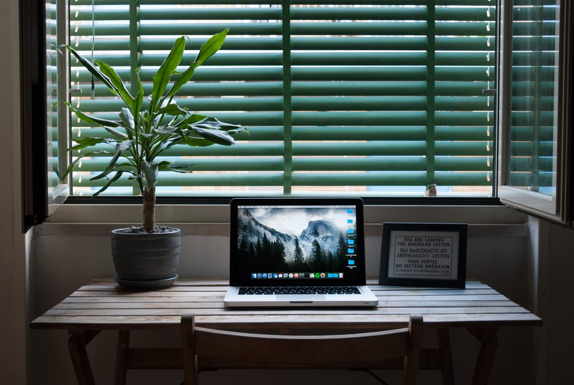 A home office with a workstation and laptop in front of a window