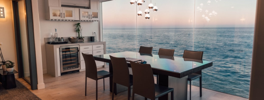 a modern dining area featuring a gorgeous metal lighting fixture and a view of the ocean
