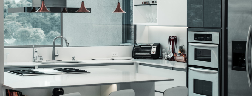 A kitchen with a counter, chairs and appliances