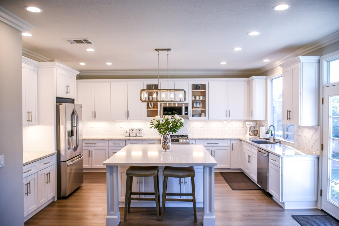 A full view of a kitchen with a counter, chairs and cabinets