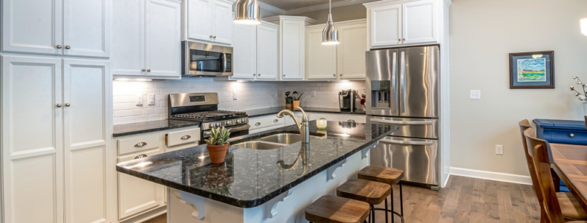 A kitchen with a marble top counter and wooden floor