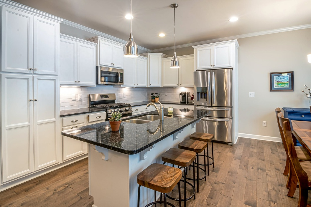 A kitchen with a marble top counter and wooden floor