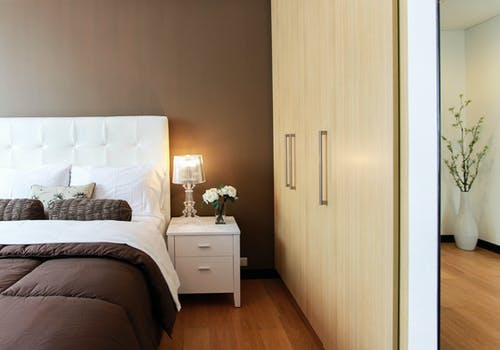 A partial view of a bedroom with a hinged door wardrobe